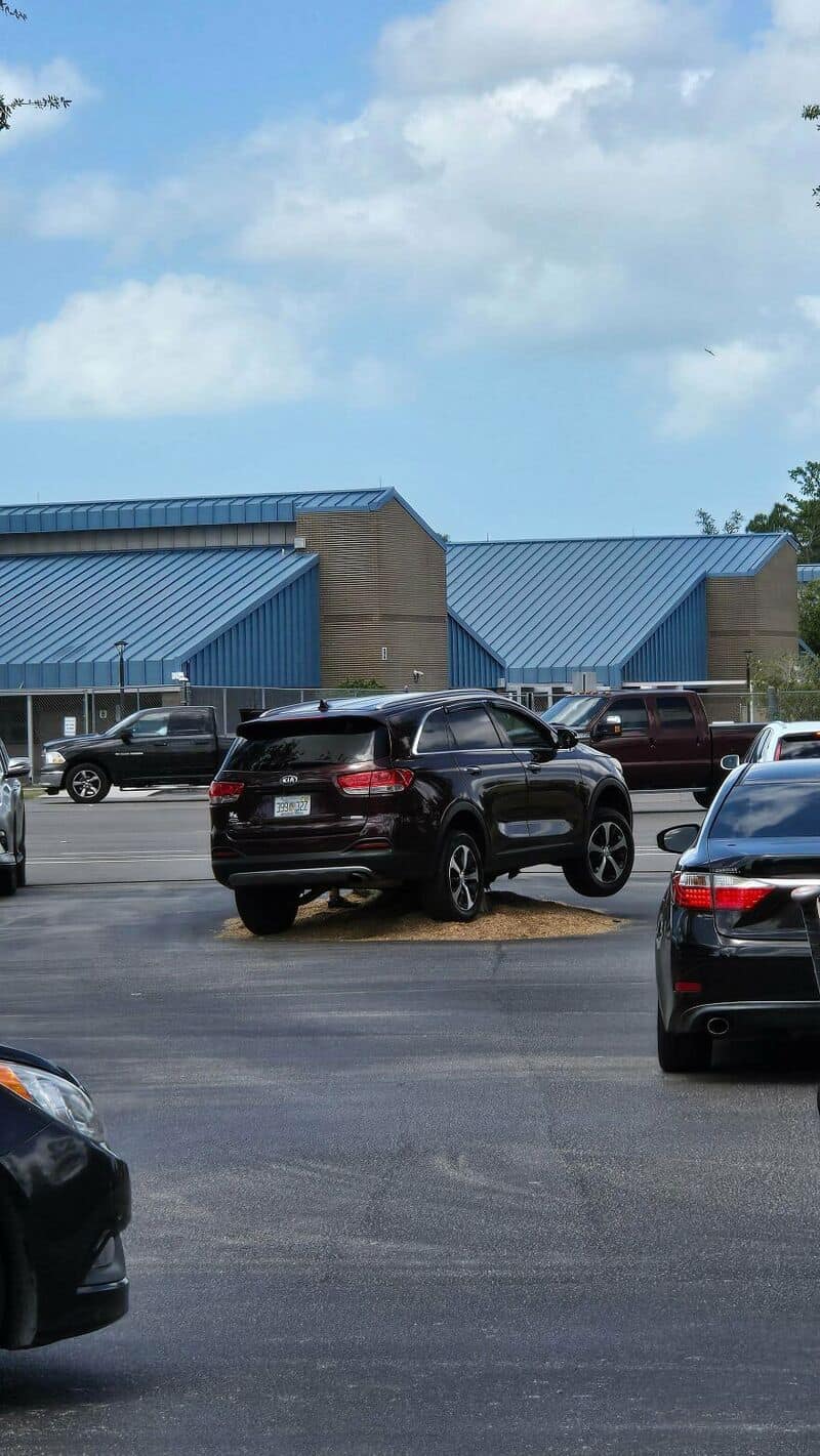 Black SUV parked on a grassy area in a parking lot.