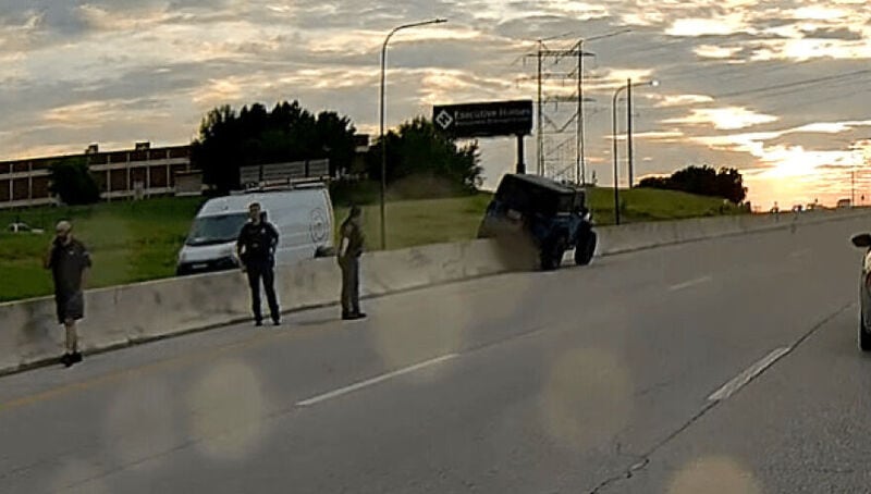Car crashes into barrier with people standing nearby at sunset.