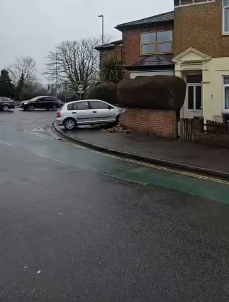 Car parked on sidewalk with large bush on top, blocking the entrance.