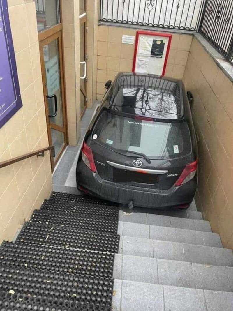Car parked in a stairwell, blocking the stairs and door.