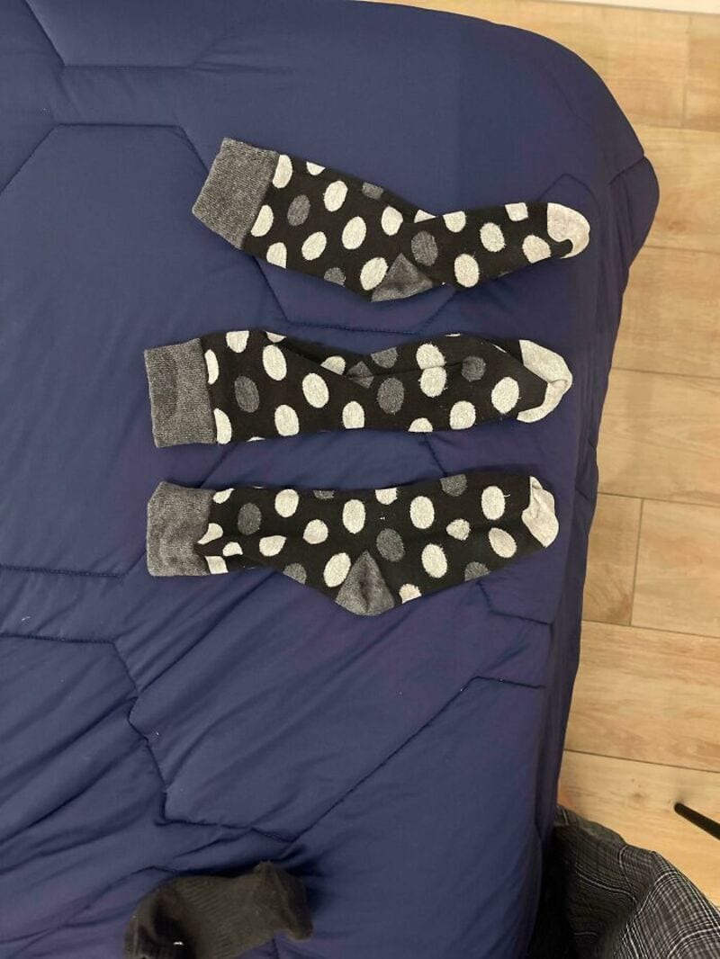 Three polka dot socks on a blue bedspread, with a wooden floor in the background.