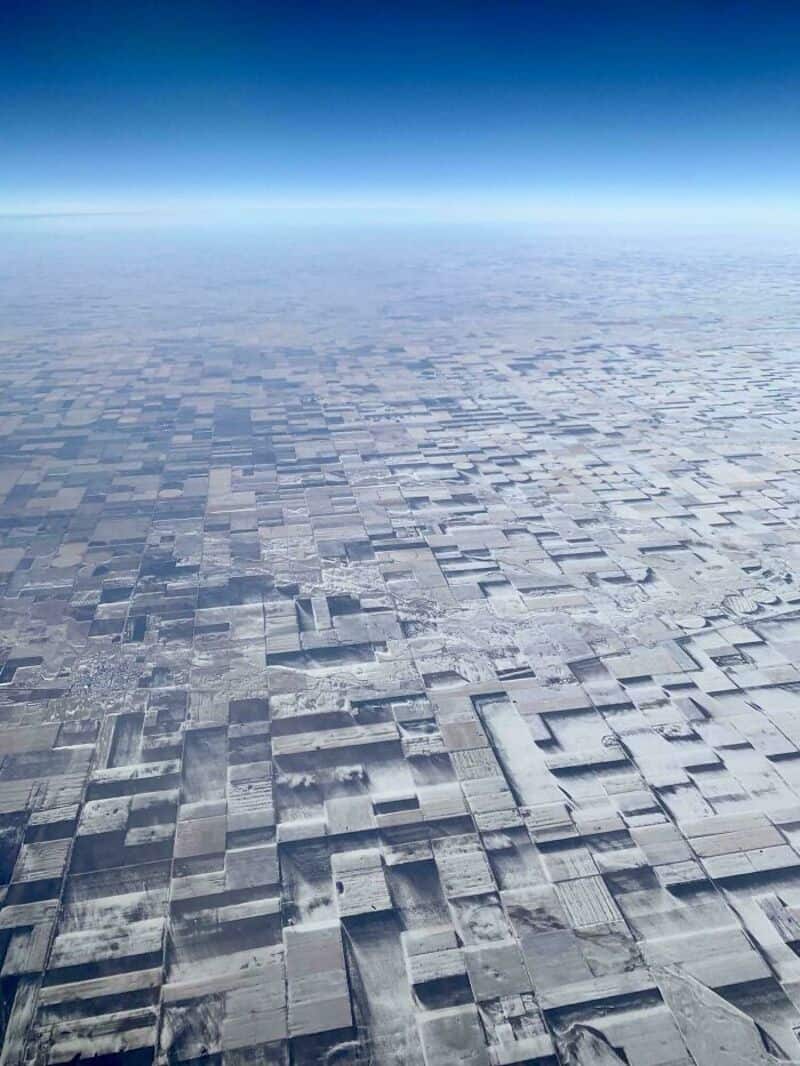 Aerial view of a grid-like snow-covered landscape with a clear blue sky.