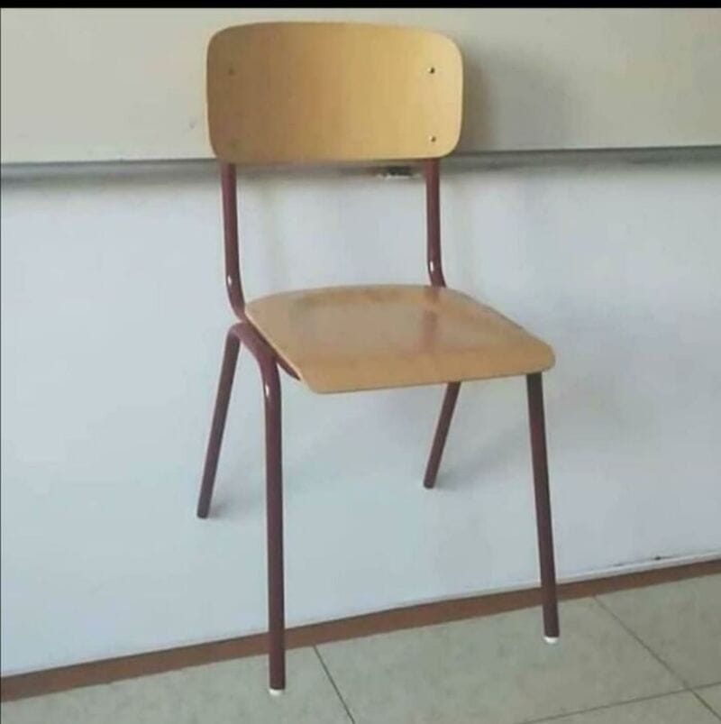 Empty wooden chair with metal legs in a classroom setting.