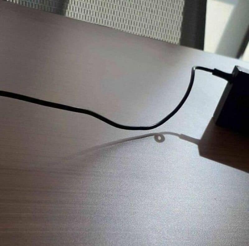 Power cord casting a shadow on the desk with a circular shadow pattern.