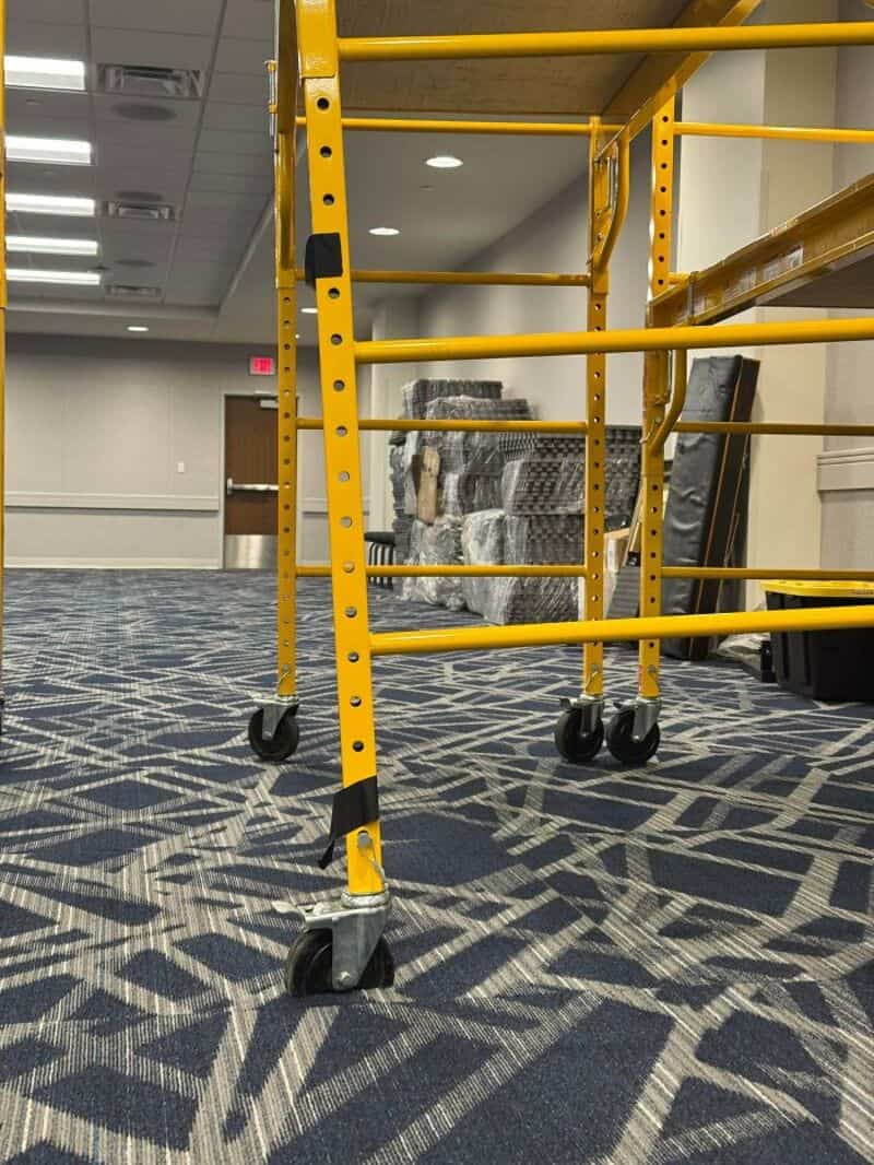 Yellow scaffolding on patterned carpet in an indoor space.