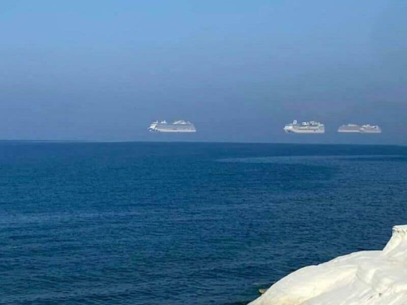 Three cruise ships floating on the ocean with a clear blue sky.