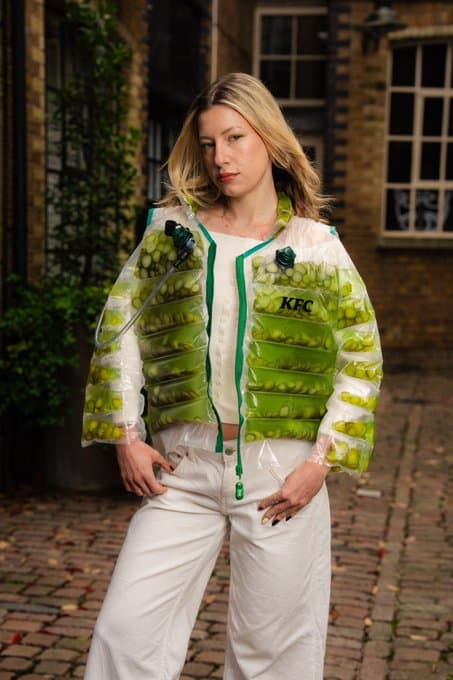 Woman in a jacket made of KFC chicken pieces, standing outdoors.