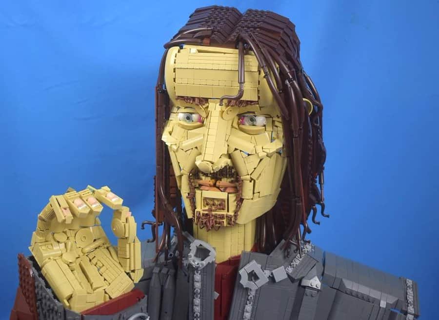 Lego sculpture of a woman with long hair and a serious expression, pointing.