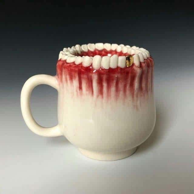 Mug designed as a set of teeth with red gums and a gold dental crown.