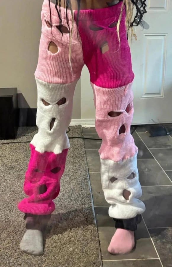Colorful distressed pants with holes, pink, white, and gray, in a home setting.