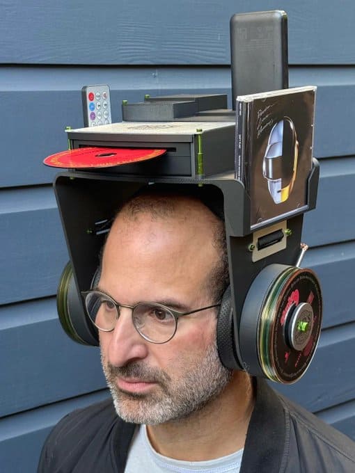 Man wearing a headset with a computer setup on his head.