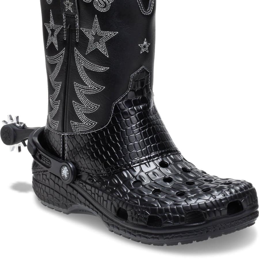 Black rain boot with star and moon designs, crocodile pattern, and adjustable strap.