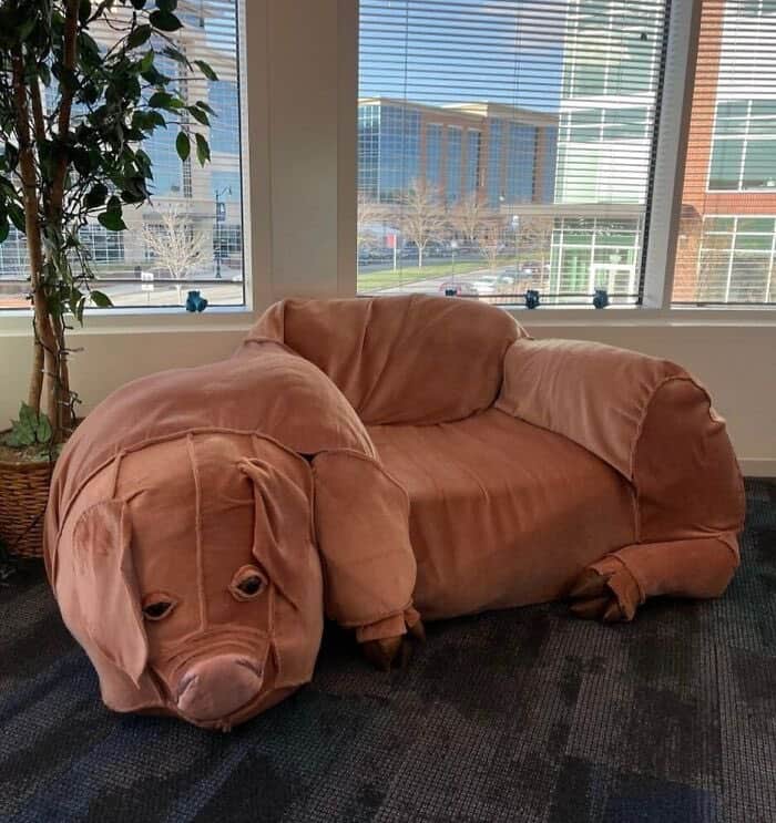 A sofa designed to look like a sleeping dog, with a dog face and ears, in an office setting.