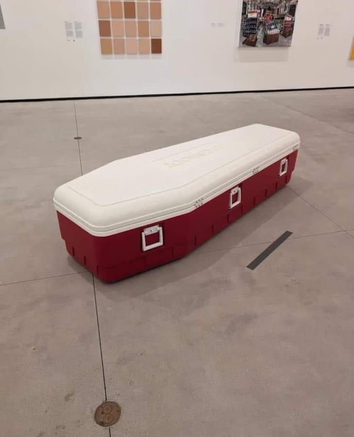 A large cooler designed to look like a coffin, with a white lid and red body.