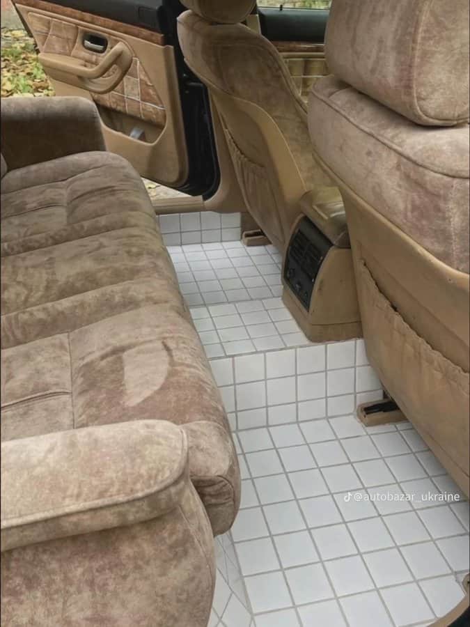 Car interior with beige fabric seats and white tiled floor.