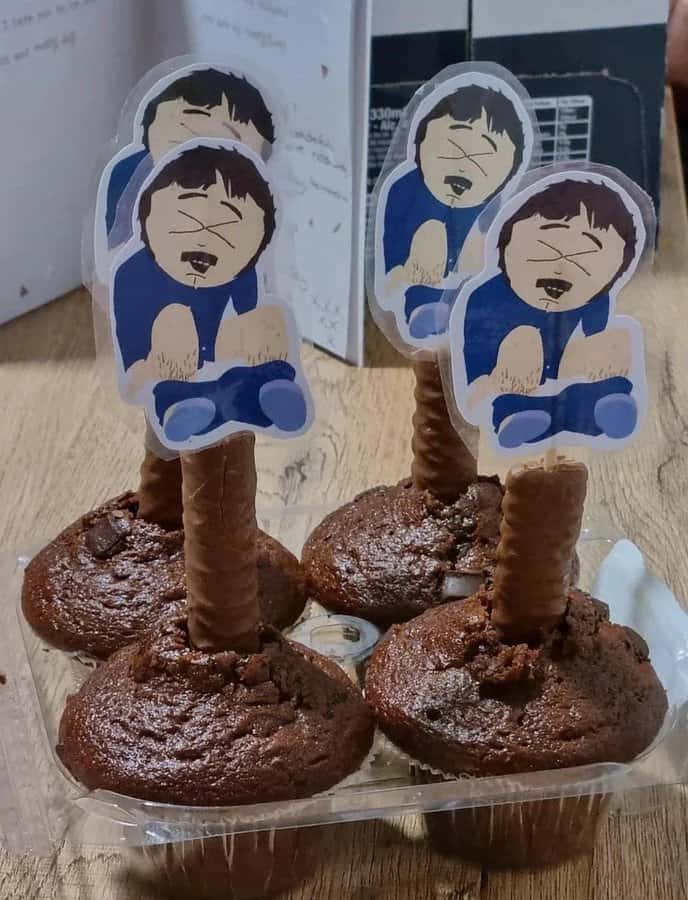 Chocolate muffins with cartoon character toppers showing laughing faces.