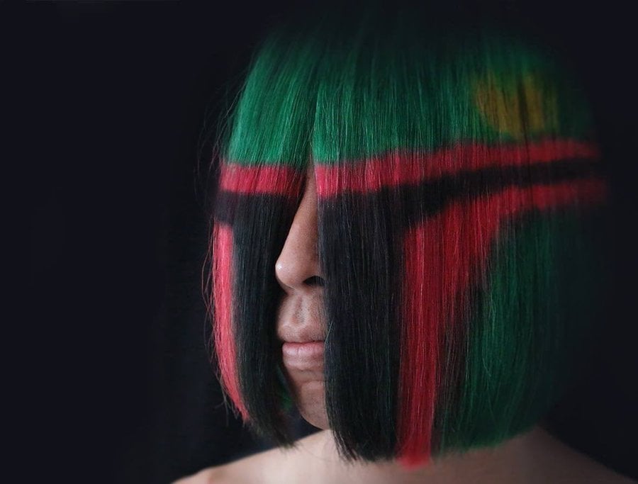 Colorful hair with green, red, and black sections, styled in a bob cut.