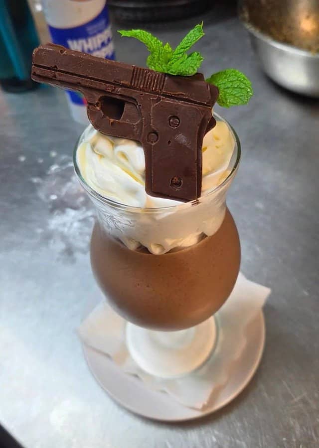 Chocolate gun-shaped dessert with mint leaves on top in a glass.