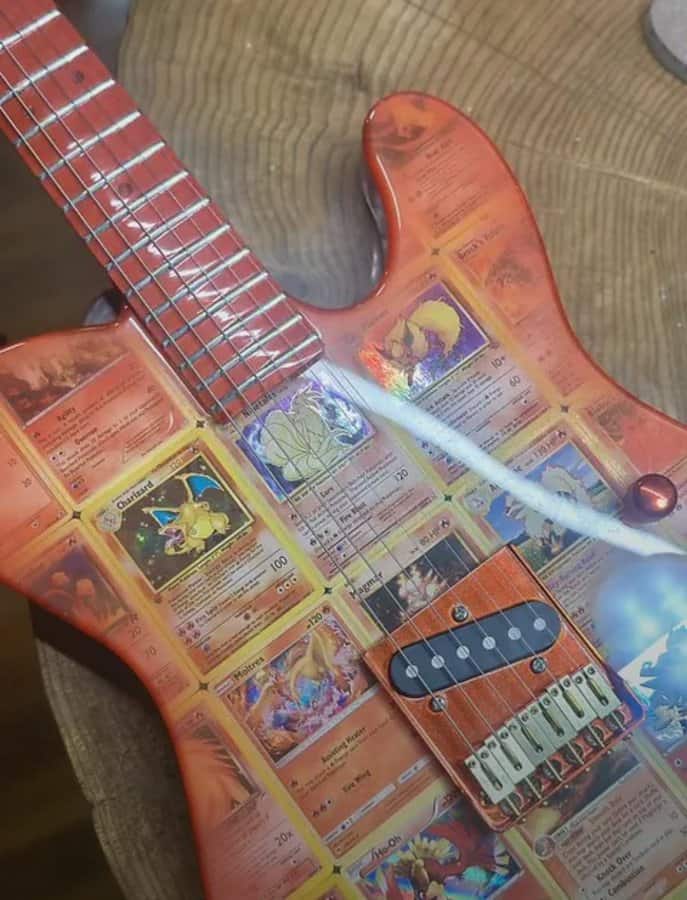Guitar with Pokémon cards as the body, placed on a wooden surface.