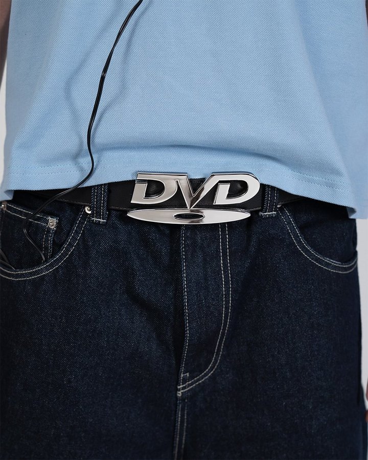 Close-up of a person wearing a DVD belt buckle with jeans and a blue shirt.
