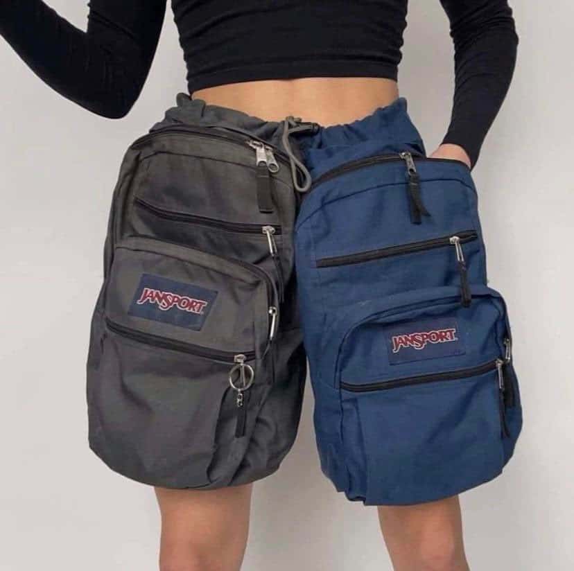 Person wearing two JanSport backpacks, one on each side, with a black crop top.
