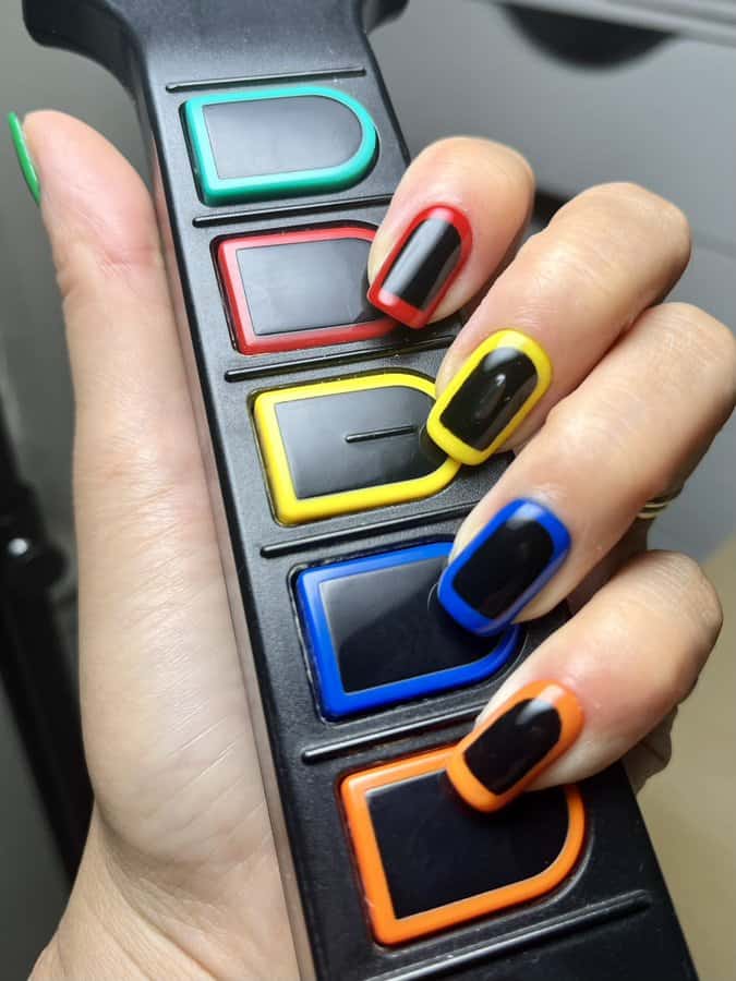 Colorful painted nails holding a remote with colored buttons.