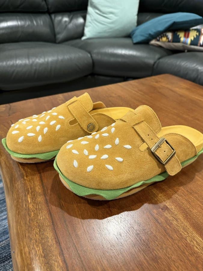 Yellow slippers with white spots and green soles on a wooden table.