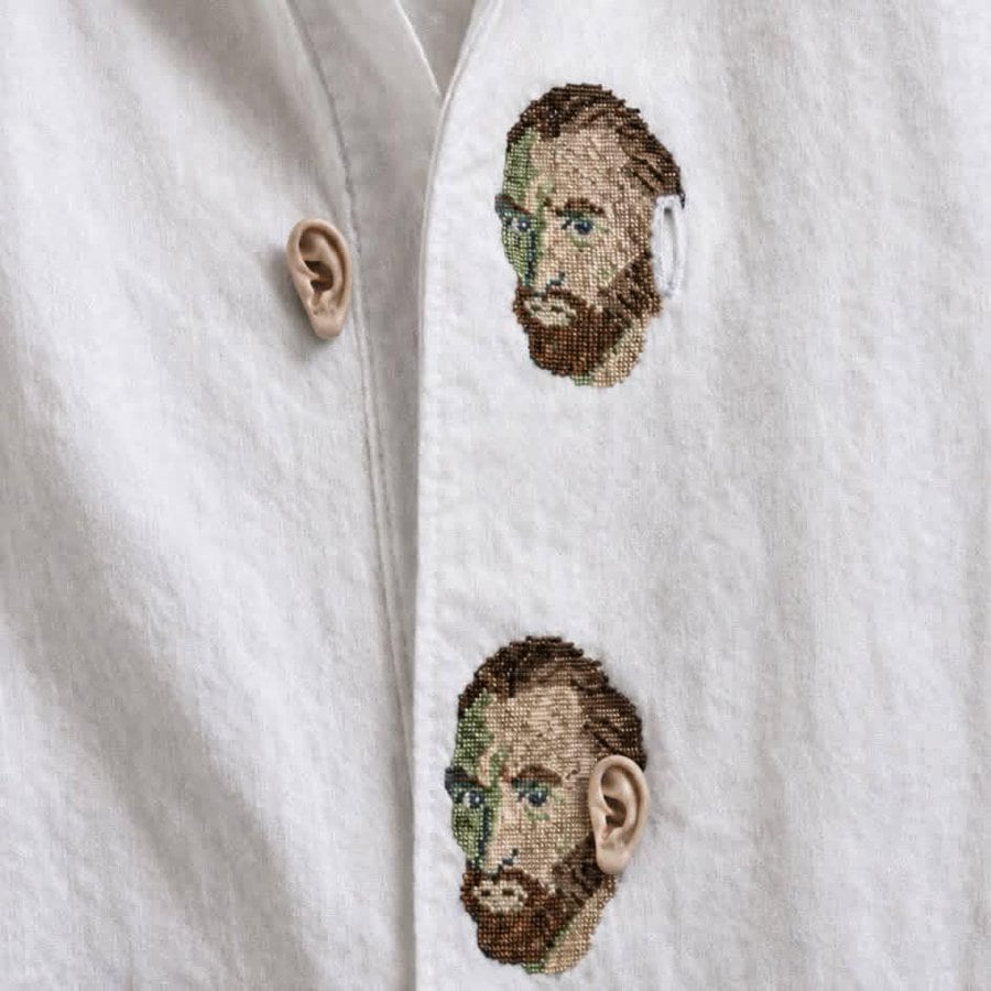 Embroidery of a man's face with beard and glasses on a white shirt.