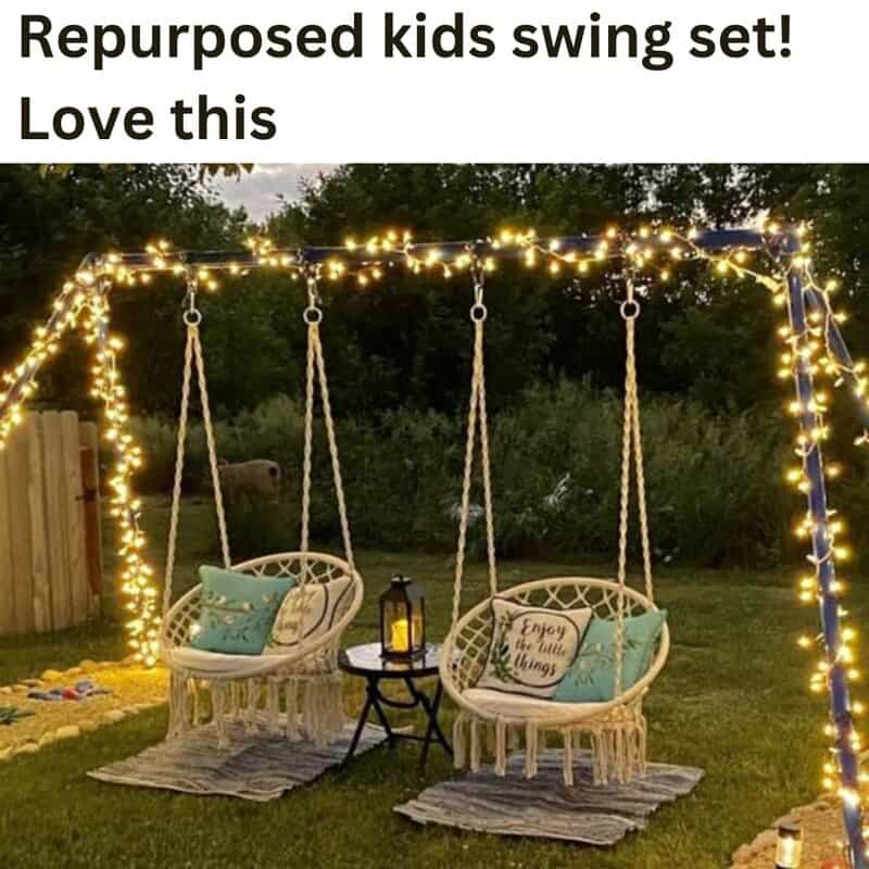 Kids swing set with two hanging chairs, string lights, and cushions in a backyard.