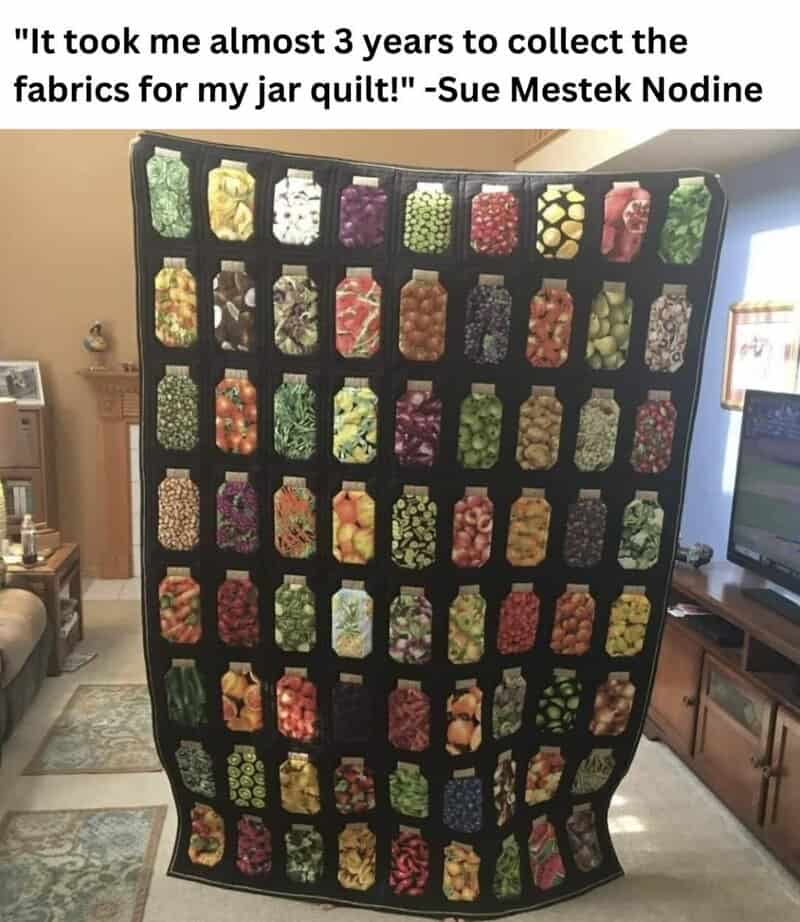Colorful jars of fabric collected for a quilt displayed on a black quilt rack.