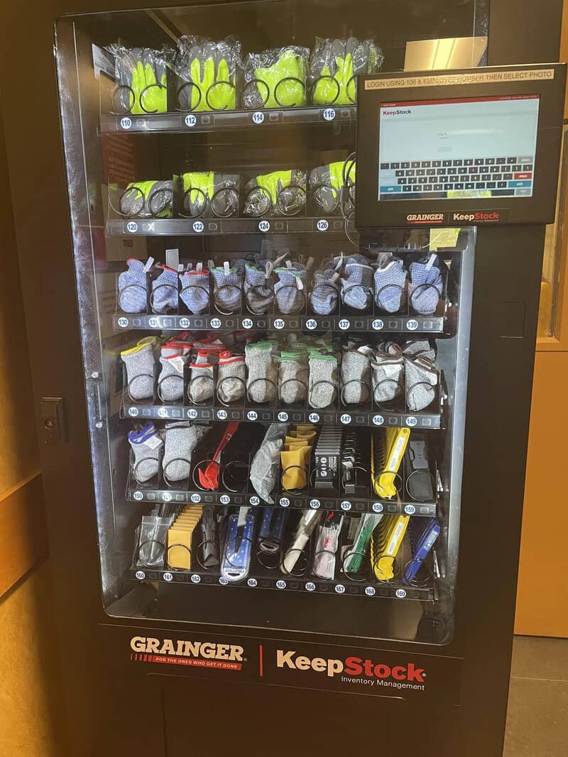 Vending machine with various sports balls and equipment, touchscreen interface on the right.