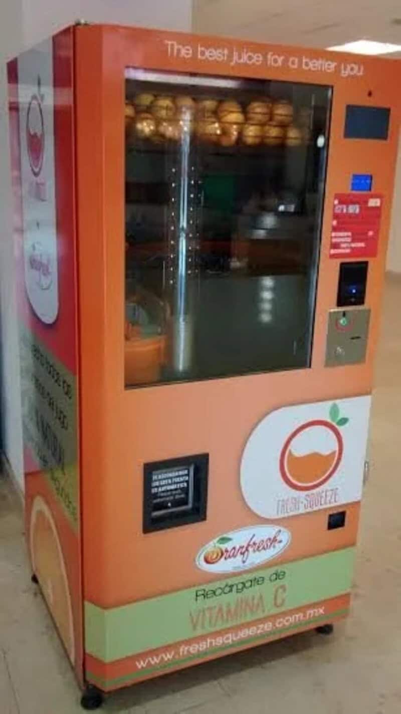Orange vending machine with juice bottles and a glass door, promoting vitamin C.