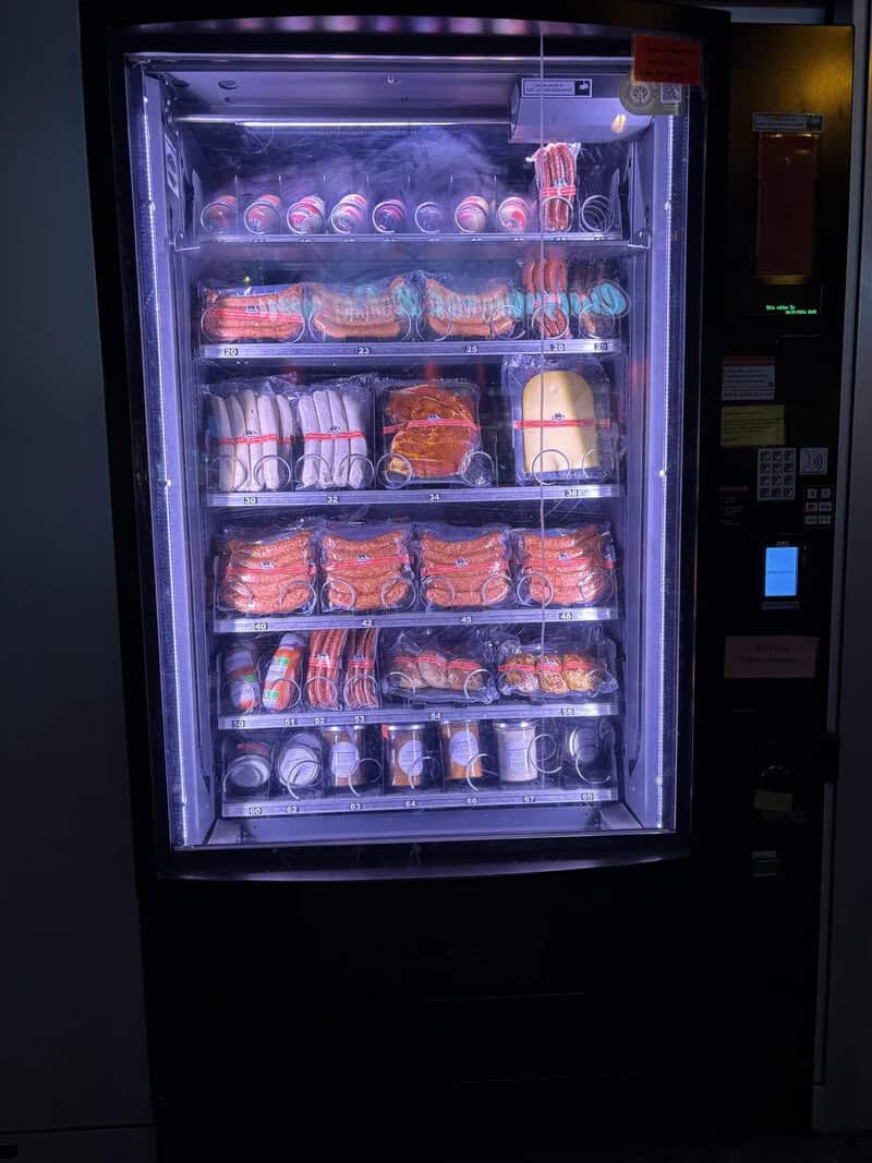 Vending machine with snacks and drinks, illuminated with blue light.