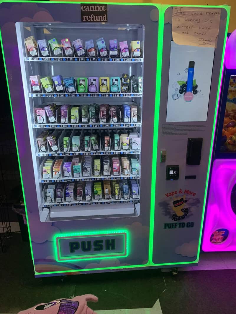 Vending machine with various phone accessories and a push button, neon lights.