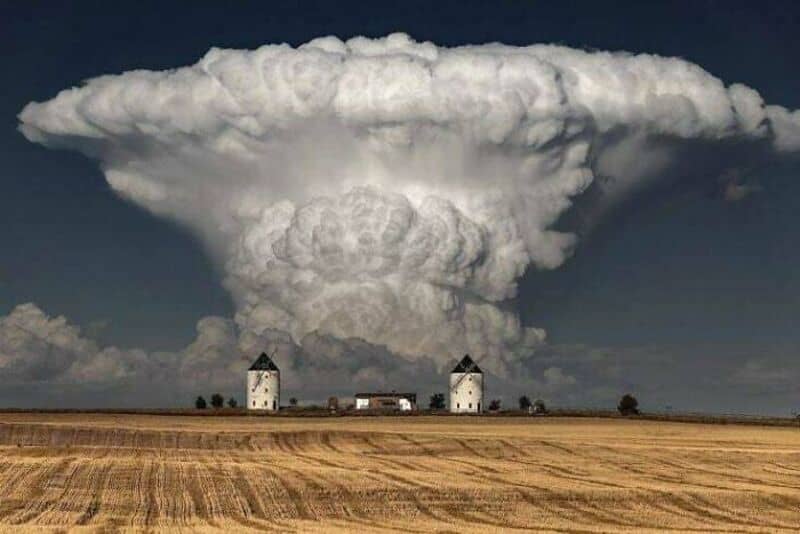 Massive mushroom cloud over a flat landscape with two small buildings.