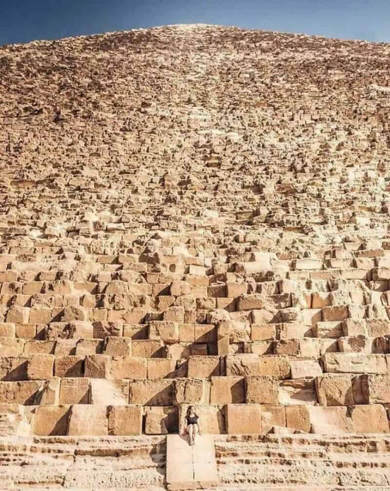 Large stone steps leading up a pyramid-like structure with a person sitting at the bottom.