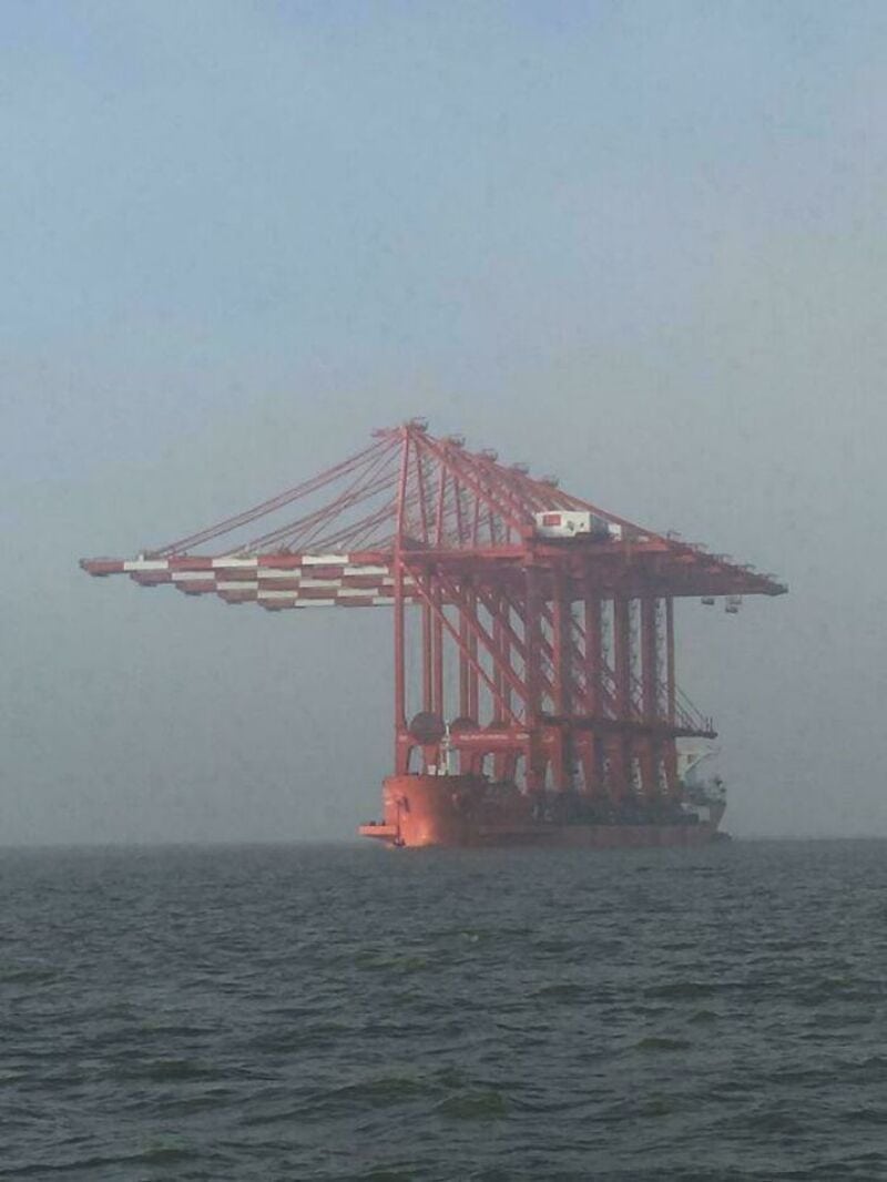 Large red crane on a barge in the water, with a foggy background.