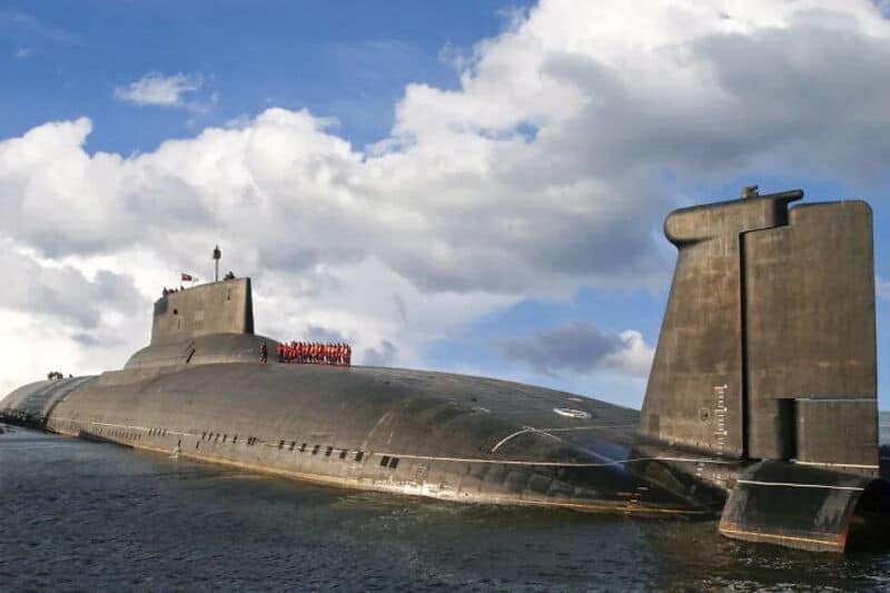 Large submarine floating on water with cloudy sky above.