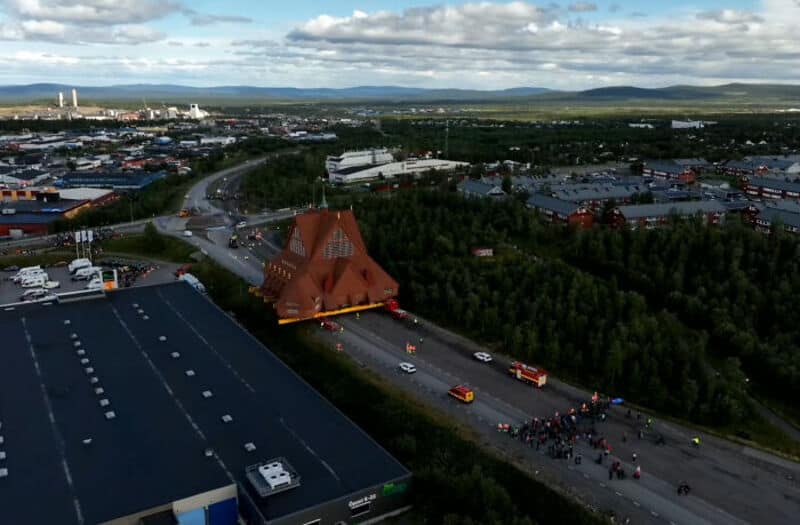 Aerial view of a large red wooden church surrounded by trees and roads.