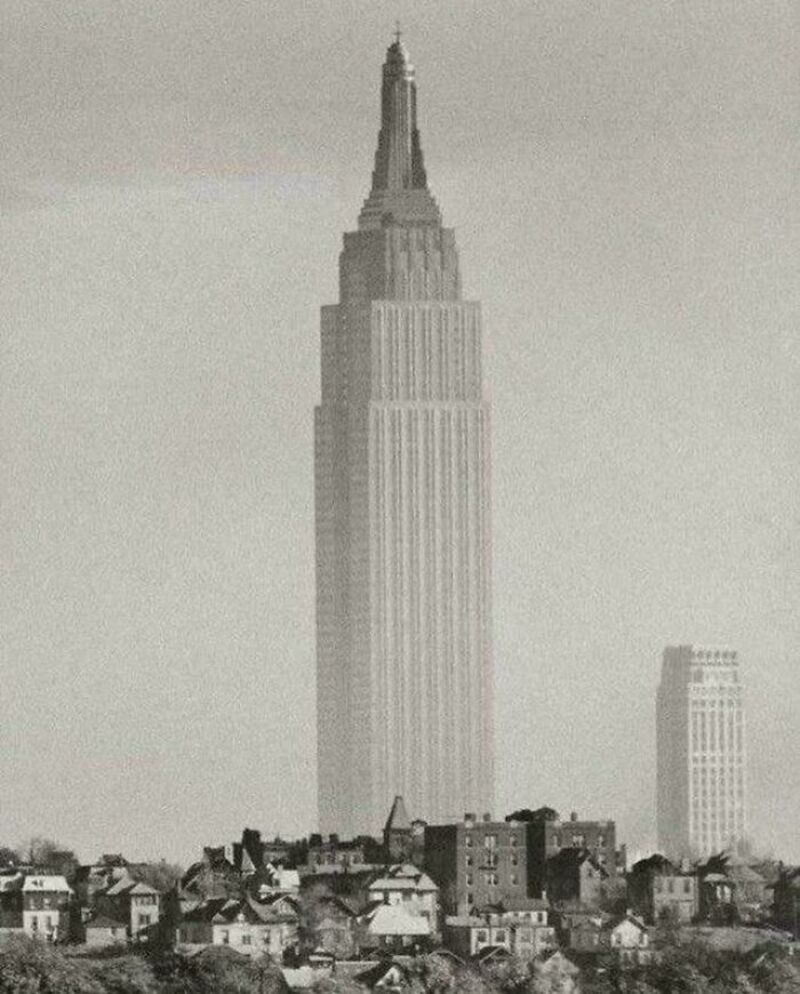 Empire State Building towering over smaller buildings in a cityscape.