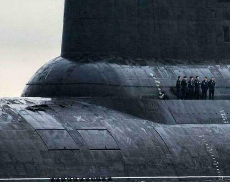 Close-up of a large submarine with a group of sailors standing on its side.