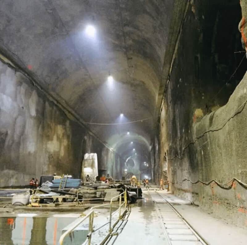 Underground tunnel construction site with lighting and equipment.