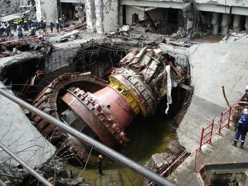 Large object, possibly a spacecraft or satellite, partially submerged in a construction site.