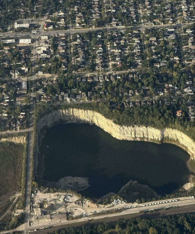 Aerial view of a large body of water surrounded by trees and residential area.