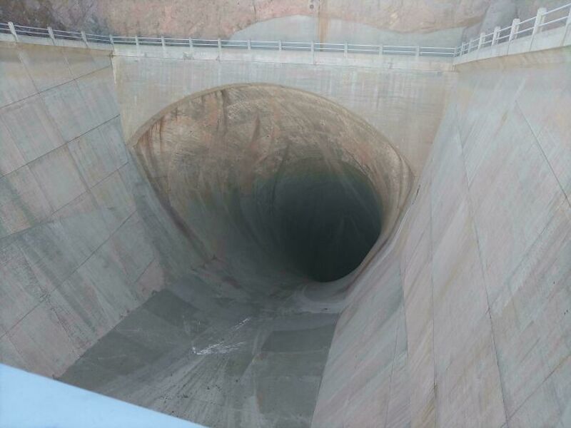 Large concrete dam spillway with a deep, dark tunnel opening.