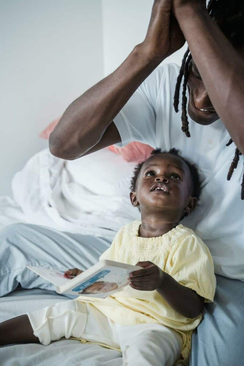Father and daughter share a joyful moment, with the father holding his head and the daughter smiling.