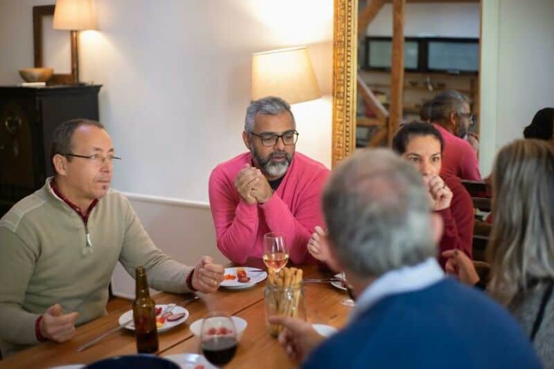 Group of adults having a discussion at a dinner table in a cozy setting.