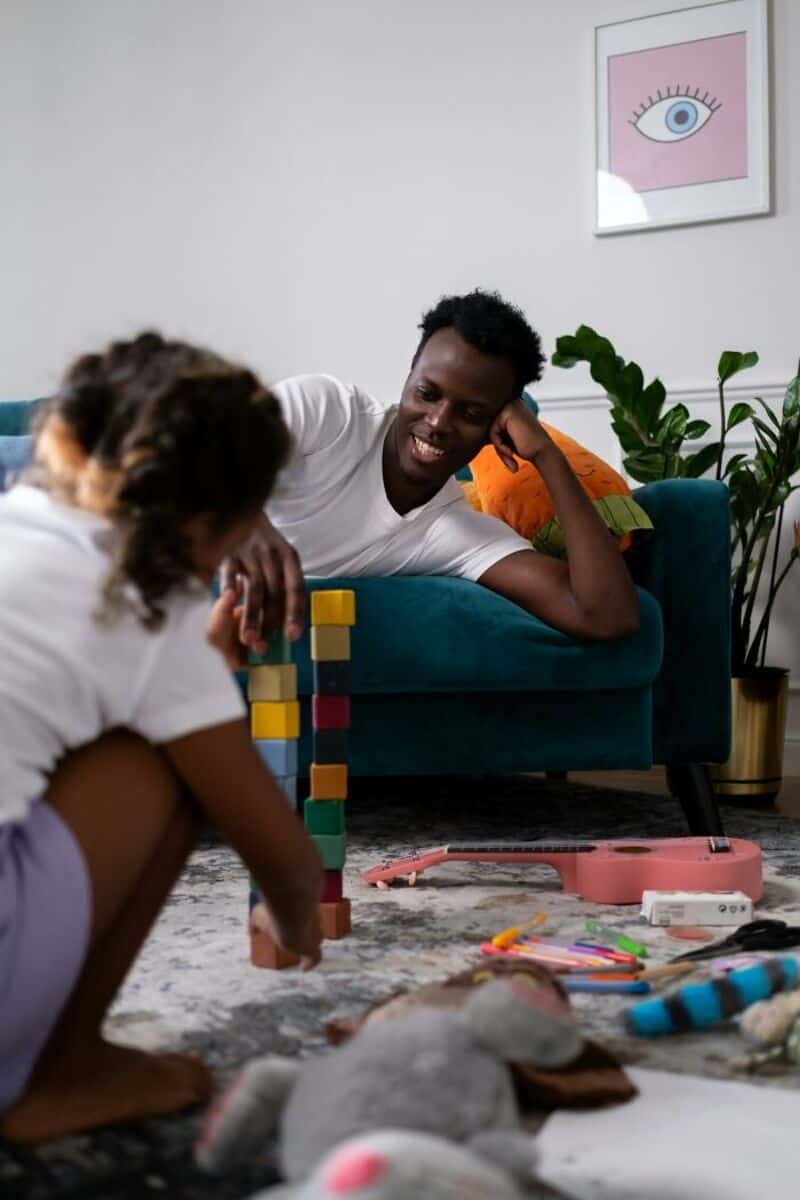 Father and daughter playing with blocks on the floor.