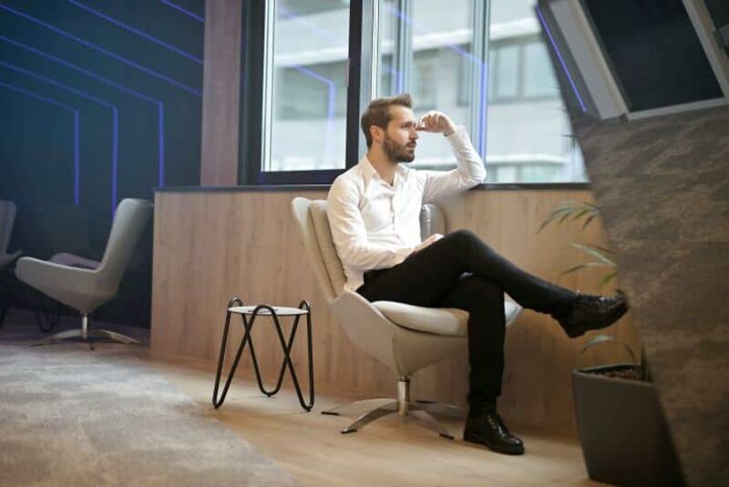 Man sitting in a modern office, looking out the window, thinking.