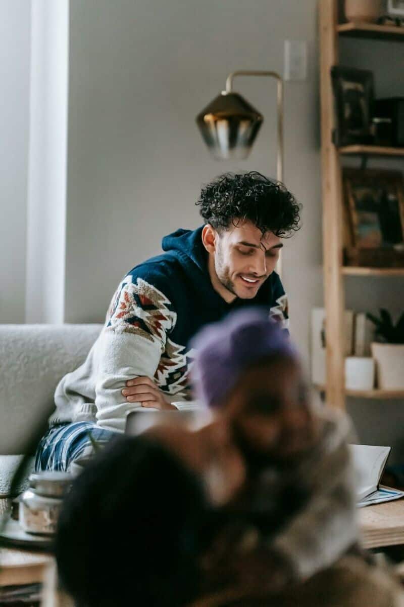Man smiling and talking to a child with purple hair in a cozy room.